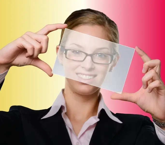 Frau mit Brille, die einen milchglasigen Spiegel vor ihr Gesicht hält.