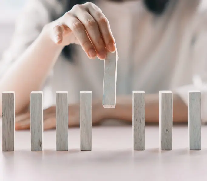 Frau, die aus einer Reihe von Bauklötzen einen herausnimmt