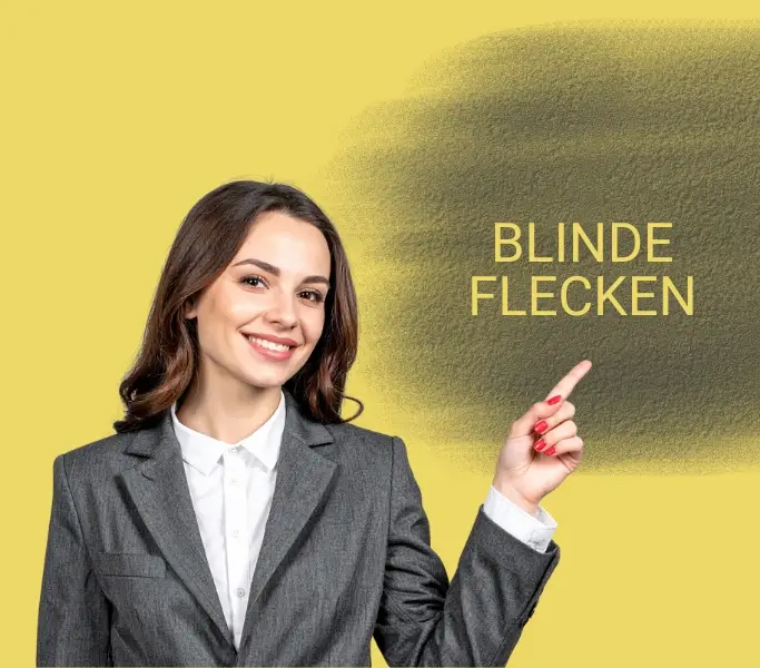 Blinde Flecken auf einem Schild im Hintergrund. Frau mit mittellangem blondem Haar in weißer Bluse und grauer Jacke zeigt auf dieses Schild.