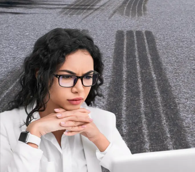 Stakeholder als Managerin mit schwarzem Haar, schwarzer Brille und weißer Jacke und fragendem Blick. Im Hintergrund Bremsspuren.