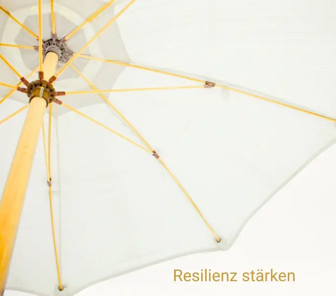 Resilienz stärken dargestellt mit einem großen weißen Sonnenschirm